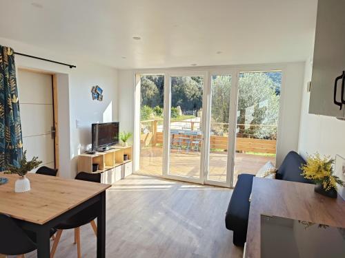 - un salon avec une table à manger et une porte coulissante en verre dans l'établissement Rez-de-jardin indépendant Ajaccio calme nature, à Ajaccio