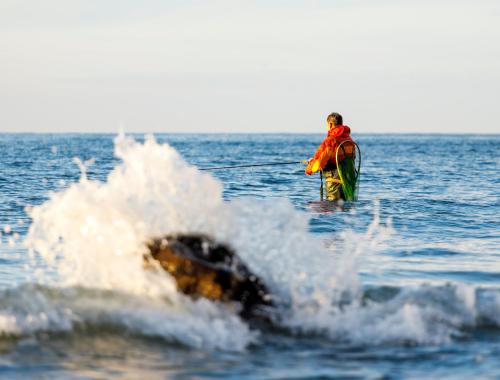 a man standing on a surfboard in the ocean at Tiny SeaSide - Loddenhøj in Lillekobbel