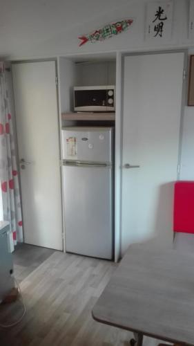 a small kitchen with a refrigerator and a microwave at Mobilhome convivial en Alsace in Munster