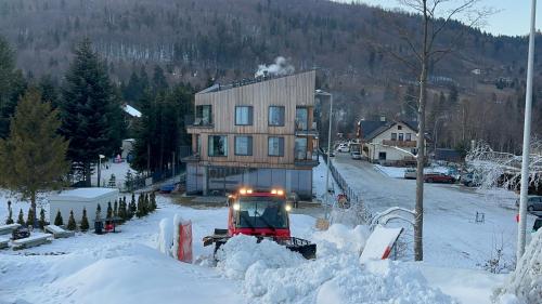a snow plow is clearing a house from snow at XYZ eXtreme You Zen in Szczyrk
