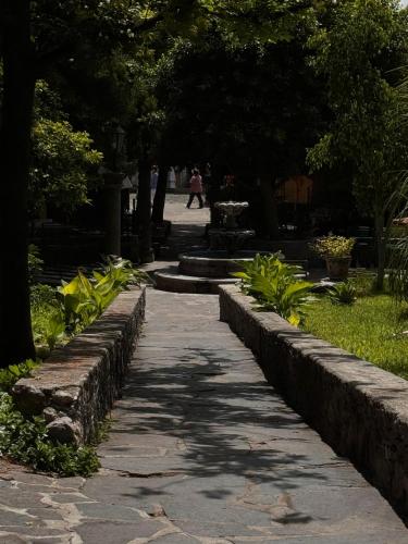 a walkway in a park with a fountain and trees at Hotel Quinta Loreto in San Miguel de Allende