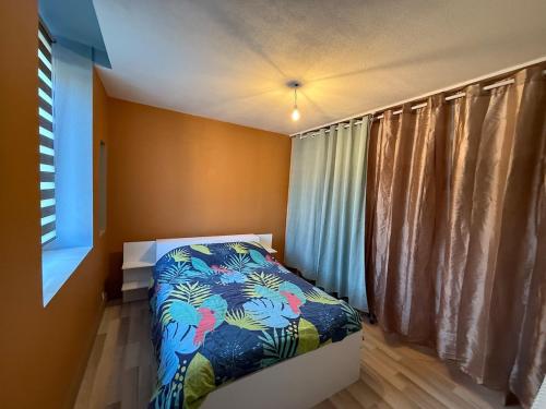 une chambre avec un lit avec une couette colorée dans l'établissement Appartement moderne avec jardin, quartier calme, à Saint-Claude