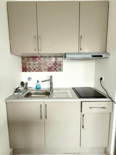 une cuisine avec des armoires blanches et un évier dans l'établissement Studio Confort Pessac Centre avec Parking, à Pessac