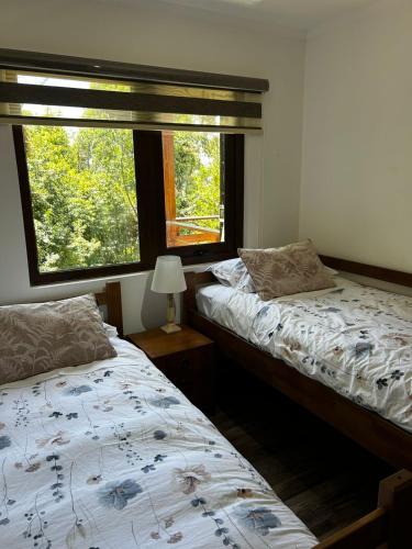 two beds in a room with a window at Cabaña en Puerto Varas, Chile. in Puerto Varas