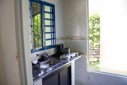 eine Küche mit Spüle und Fenster in der Unterkunft Pousada Estância Vip in Cunha