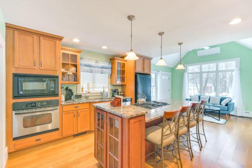 a kitchen with wooden cabinets and a kitchen island with bar chairs at 16 Mi to Boston Home with Deck in Weymouth in Weymouth