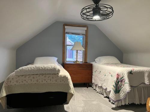 a attic bedroom with two beds and a window at James Romans Enigma House in Berea
