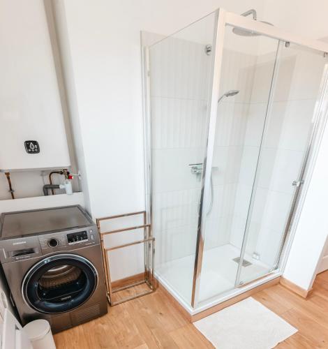 une machine à laver et une douche dans une chambre dans l'établissement maison R&vâmes, à Calais