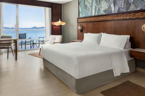 a bedroom with a large white bed and a balcony at The Westin Playa Bonita Panama in Playa Bonita Village