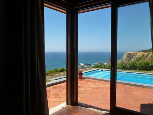 a room with a view of the ocean from a window at Herdade AMÁLIA RODRIGUES in Zambujeira do Mar
