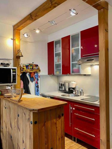 une cuisine avec des armoires rouges et un comptoir dans l'établissement Vue mer, balcon, 50m plage & village, au calme - centre ville historique, 2P pour 4 maximum, à Villers-sur-Mer