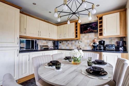 a kitchen with white cabinets and a table and chairs at Luxury - 4 BHK Semi Detached House in Chelmsford