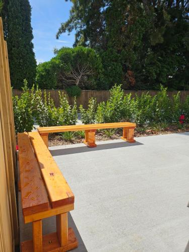 a wooden bench sitting on top of a sidewalk at Evolve! Brand new home on Pioneer mins from PN CBD in Palmerston North