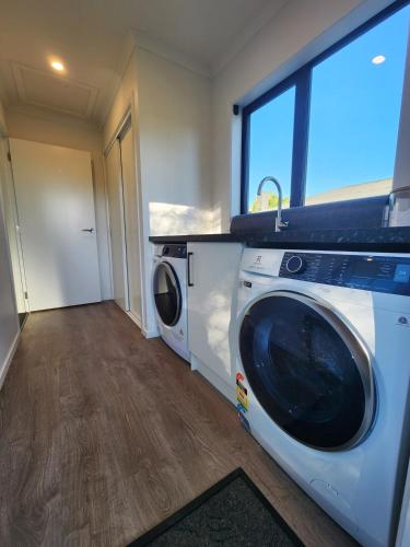 a laundry room with a washer and dryer at Evolve! Brand new home on Pioneer mins from PN CBD in Palmerston North