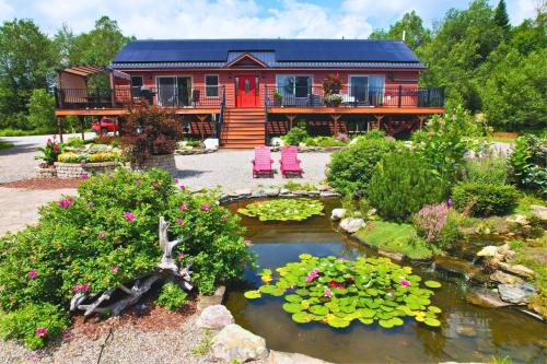 a log cabin with a pond in front of a house at Stunning Family Compound for Events and Large Groups in Bretton Woods in Bretton Woods
