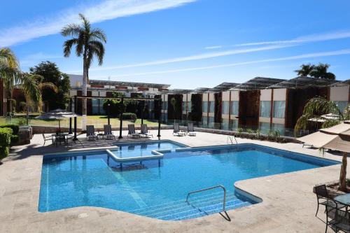 a large swimming pool with chairs and a building at voco Hermosillo by IHG in Hermosillo