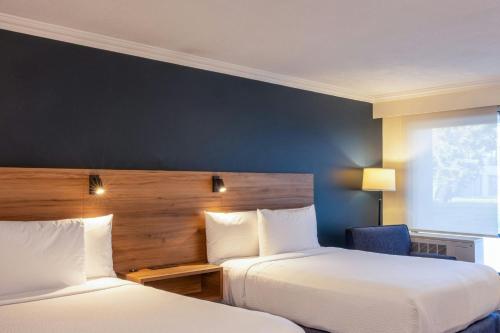 a hotel room with two beds and a chair at Courtyard Toluca Airport in Toluca