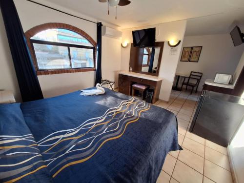 a bedroom with a bed with a blue and yellow blanket at Motel Jabaloyas in Tijuana
