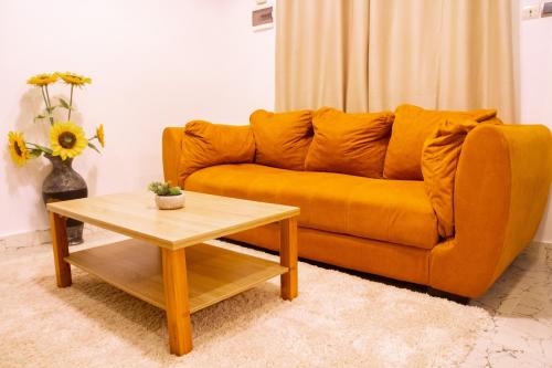 an orange couch in a living room with a coffee table at Bkap Apparts - Calme, proche des commerces, de l aéroport, de la plage et du centre-ville in Cotonou