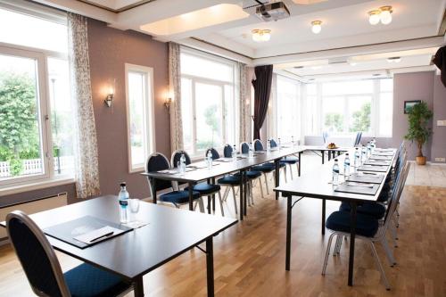 a row of tables and chairs in a room with windows at Hotel Wassilioff - Unike Hoteller in Stavern