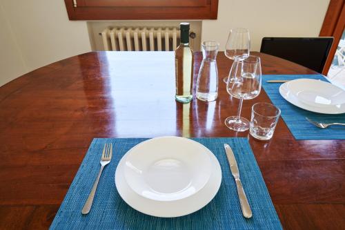 Casa Ambra la tranquillità in centro città في بادوفا: طاولة خشبية مع لوحة بيضاء وكؤوس للنبيذ