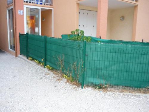 a green fence in front of a building at Barcarès F2 cabine, RDC, plage 50 m, 28 m2, 6 personnes in Le Barcarès