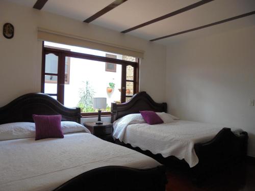 twee bedden in een kamer met een raam bij Hospederia Villa Berenita in Villa de Leyva