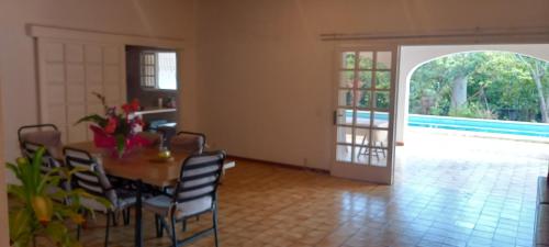 a dining room with a table and chairs and a pool at séjour chez l'habitant mpdf nouméa in Noumea