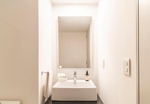 a white bathroom with a sink and a mirror at Kukun Reforma & Downtown in Mexico City