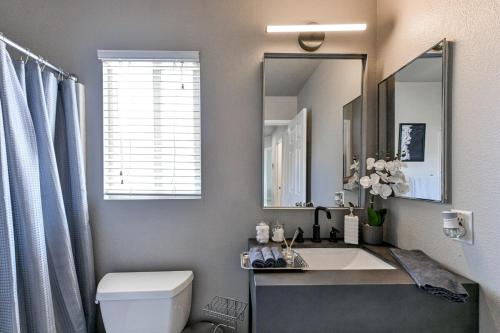 a bathroom with a sink and a toilet and a mirror at Vila Amor- Pool, Games and Ultimate Vegas Vibes in Las Vegas
