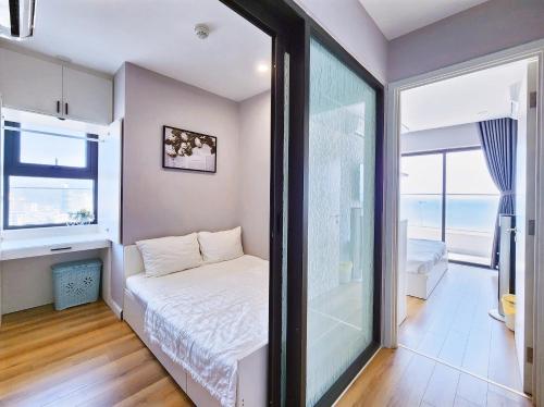 a small bedroom with a bed and a large window at Seafront Apartment TMS Quy Nhơn in Quy Nhon
