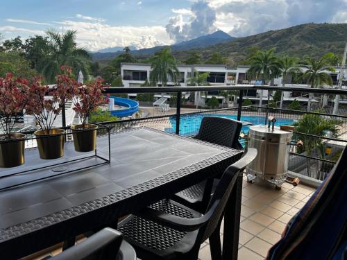 a balcony with a table and chairs and a swimming pool at Hermoso apartasol en santafe de Antioquia. in Santa Fe de Antioquia