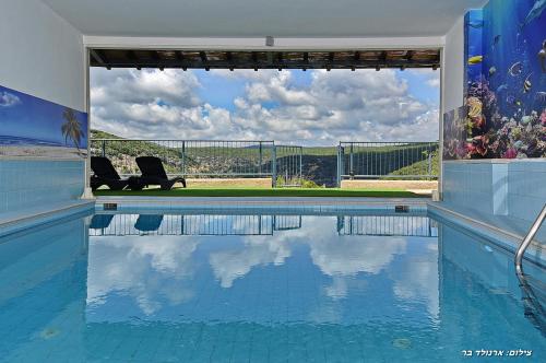 a swimming pool with two chairs sitting next to it at אחוזת נחל כזיב in Ma'alot Tarshiha