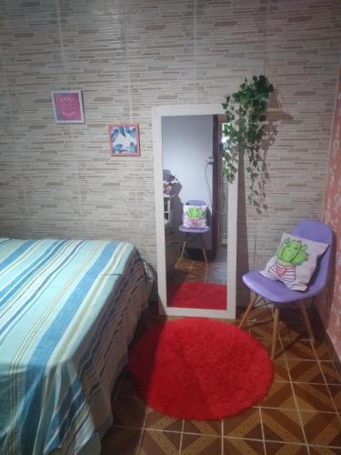 una camera da letto con un letto, una sedia e uno specchio di Quarto centro Sao thome casa a São Thomé das Letras