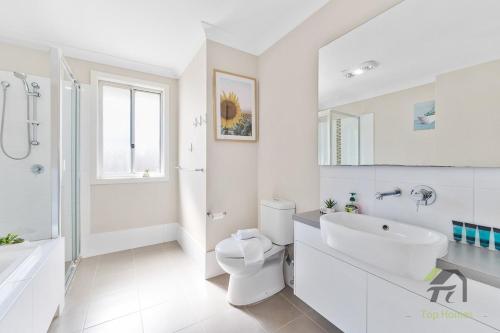 a white bathroom with a toilet and a sink at The dream world of bindo in Schofields