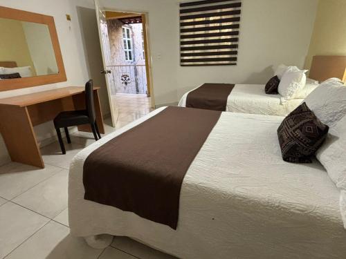 a hotel room with two beds and a desk and a table at Pequeno Gran Hotel in Aguascalientes