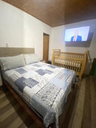 a bedroom with a bed with a tv on the wall at Casa da Vica in São Gabriel