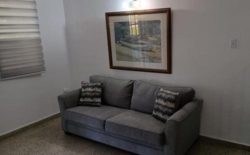 a couch in a living room with a picture on the wall at San Antonio in Aguas Buenas