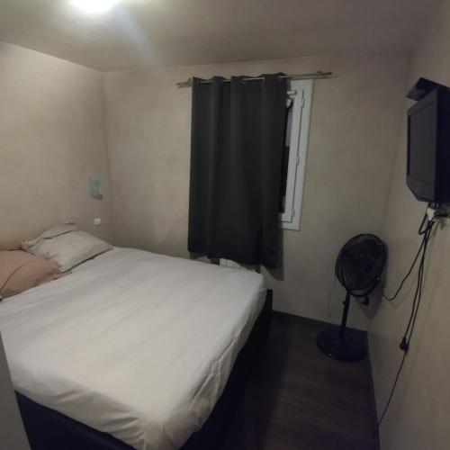 une petite chambre avec un lit et une télévision dans l'établissement T3 calme et lumineux, à Menton