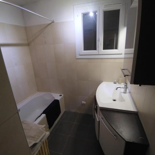une salle de bain avec un lavabo et une baignoire dans l'établissement T3 calme et lumineux, à Menton
