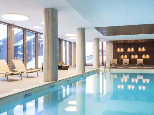 une piscine avec chaises et tables dans un bâtiment dans l'établissement Chalet in French Alps with Premium Comfort, à Hauteluce
