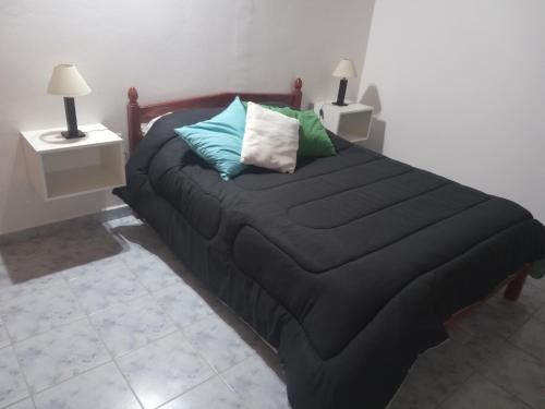 ein Bett mit einer schwarzen Decke und Kissen darauf in der Unterkunft Postal del Golfo in Las Grutas