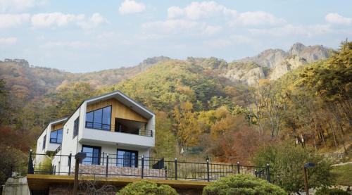 a house on a bridge with mountains in the background at Damyang Lisa Forest Village in Damyang