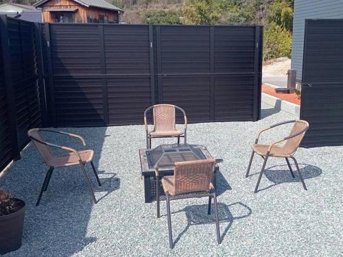 a patio with three chairs and a table and a fence at しまなみ海道 COTTAGE Umimae in Onomichi