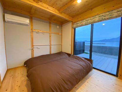 a bedroom with a bed and a large window at しまなみ海道 COTTAGE Umimae in Onomichi