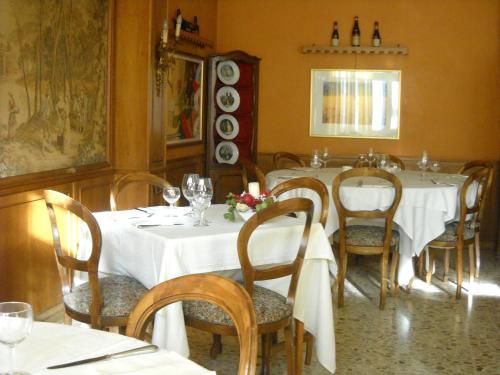 un comedor con una mesa con mesas y sillas blancas en Hotel Regina, en Pinerolo