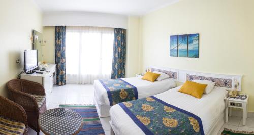 a hotel room with two beds and a television at Lotus Bay Resort in Hurghada