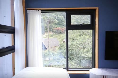 a bedroom with a large window with a view at Damyang Lisa Forest Village in Damyang
