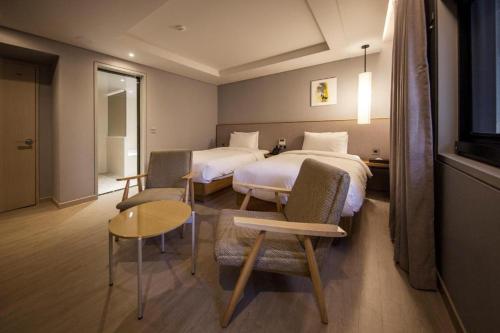 a hotel room with two beds and a table and chairs at Hound Hotel Yeonsan in Busan