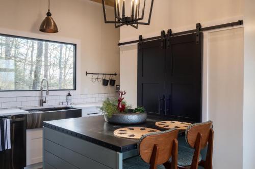 a kitchen with black cabinets and a table with chairs at A Red River Barnhouse in Rogers